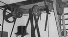 Historischer Antrieb mit Riemen und Schwungrädern in einer Werkstatt; möglicherweise frühe Technik bei Melzig.